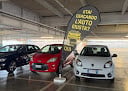 Car dealership showroom interior with red and white vehicles displayed under bright overhead lighting